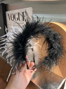 Detailed close-up of black and white ostrich feather headband, fluffy soft texture.