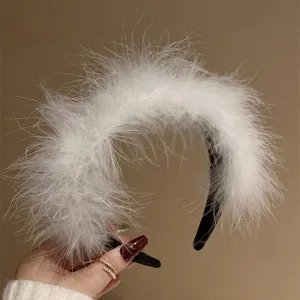 Fluffy white feather headband detail, soft ostrich feather texture on a black band close-up.