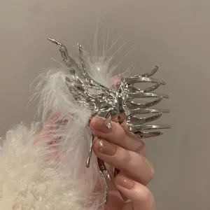 Detail shot of a silver liquid metal butterfly hair claw clip decorated with fluffy white feathers.