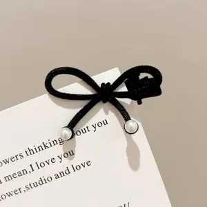 Close-up detail of black velvet bow hair clip with pearl ends, elegant sweet side hair accessory.