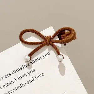 Brown velvet bow hair clip with elegant pearl details, exquisite close-up product view.