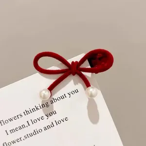 Close-up detail of red flocked pearl bow hair clip, showing cute side bang design.