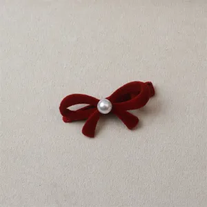 Close-up detail of the red velvet bow hair clip with pearl embellishment, cute and stylish.