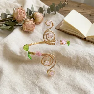 Dettaglio del bracciale da braccio a spirale con fiori di acrilico rosa e filo dorato.