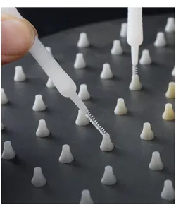 Close-up detail of a white mini cleaning brush tackling shower nozzle holes effectively.