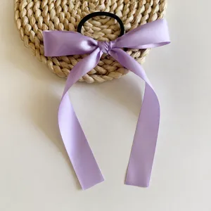 Gros plan d'un joli chouchou ruban nœud violet clair, texture satinée élégante pour tous les jours.