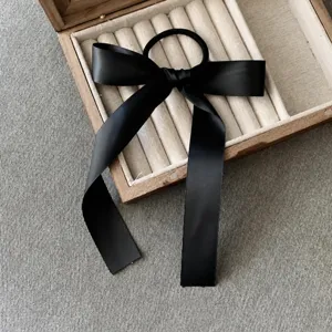 Détail chouchou nœud papillon en satin noir, élégante corde à cheveux pour le style quotidien.