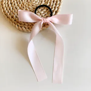 Détail de l'élastique à cheveux en ruban satin rose, joli nœud long pour coiffure douce et quotidienne.