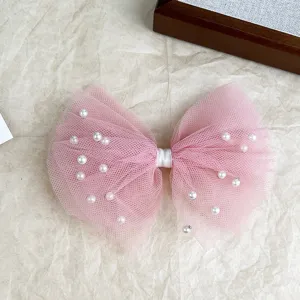 Close-up detail of the pink mesh pearl bow hairpin, showing delicate tulle and white beads.