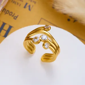 Makro-Detail eines vergoldeten Edelstahlrings mit mehreren Bändern und Zirkoniasteinen.