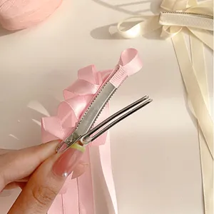 Primo piano di molletta per capelli con fiocco rosa e lunghi nastri eleganti con clip metallica.