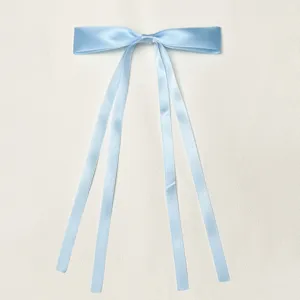 Light blue ribbon bow detail, double streamer hair accessory close up shot, elegant style.