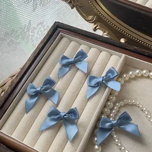 Close-up detail view of cute blue satin bow mini hair clips displayed neatly on a tray.