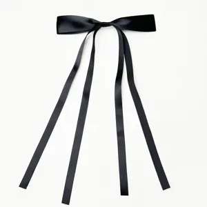 Close up of black satin ribbon hair bow with long streamers, elegant hair accessory detail.