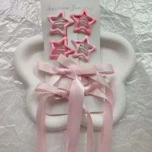 Primo piano di fermagli per capelli a stella rosa con lunghi nastri di raso sulla carta.