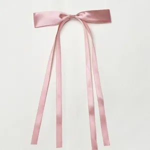 Close-up detail of the elegant pink satin bow hair clip, featuring smooth glossy ribbon and fine stitching.