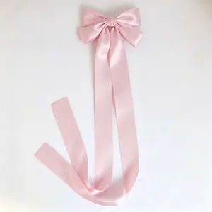 Close-up detail of the pink satin hair bow featuring elegant long ribbons for cute styling.