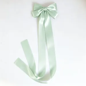 Close-up of mint green satin bow hair clip with long flowing ribbons, elegant hair accessory detail