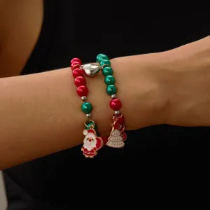 Gros plan de bracelets de Noël en perles rouges et vertes avec breloques Père Noël.