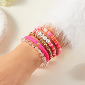 Detail van roze polymeerklei armbanden met gouden kralen en witte 'LOVE' letterkralen.