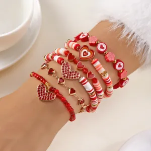 Detailopname van een 6-delige set stapelbare armbanden met rode hartjes en bloemen