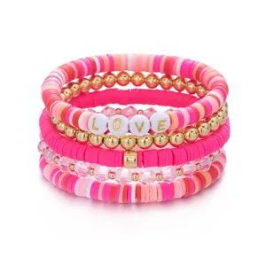 Close-up van roze polymeerklei kralenarmbandenset met gouden LOVE-bedeltjes voor Valentijnsdag