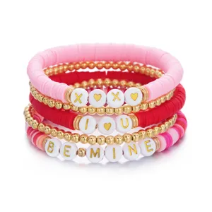Detailweergave van roze en rode polymeerklei armbanden met gouden BE MINE en XOXO tekst.