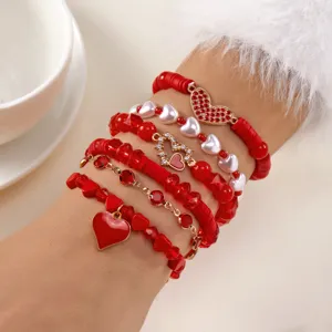 Detail van een 6-delige rode polymeerklei armbandenset met hartjes en witte parels