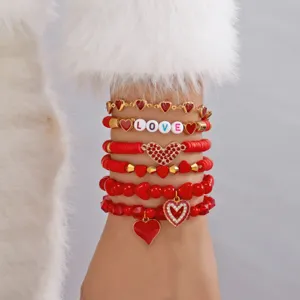 Close-up van een 6-delige rode hartjes armbandset met LOVE letters en kleikralen.