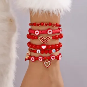 Gedetailleerde macro-weergave van de rode armbandenset met hartvormige bedeltjes