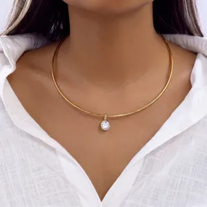 Gros plan du collier torque minimaliste en acier doré avec pendentif en zircone