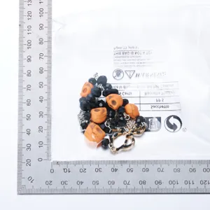 Detail of Halloween necklace with spider pendant and skull beads next to ruler