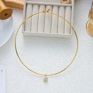 Gros plan d'un ras-du-cou en acier inoxydable doré avec un pendentif en zircone.