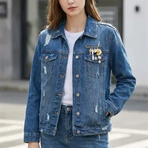 Close-up showing a gold marine-themed brooch with starfish and pearls on a denim jacket.