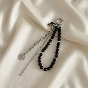 Dettaglio di un elegante ciondolo per borsa con perle nere e moneta d'argento