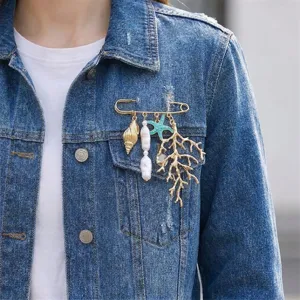 Detailed view of an ocean-themed brooch with pearls and coral on a denim jacket.