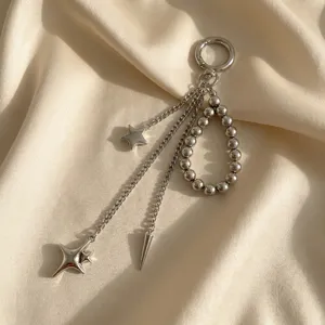Dettaglio di un ciondolo borsa argento con stelle e perle metalliche su sfondo di seta