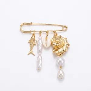 Detailed view of gold safety pin brooch featuring ocean charms and baroque pearls.