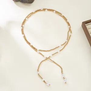 Detail of elegant long gold beaded wrap necklace with delicate white pearls in Y-shape