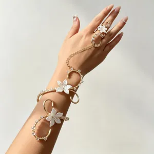 Bracelet de bras élégant en fil doré avec fleurs blanches et cristaux relié à une bague
