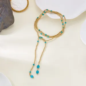 Detailed view of long gold wrap necklace featuring turquoise-colored beads in Y-shape