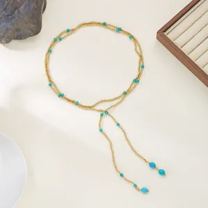 Detail view of a stylish gold Y-necklace featuring turquoise beads and long tassel fringes