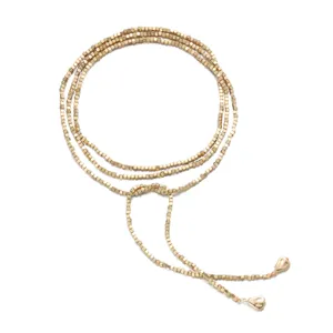 Detail view of long gold wrap necklace with small cubic beads and heart shaped tassels