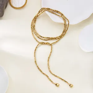 Detailed view of a gold wrap necklace featuring square beads and heart-shaped tassels.