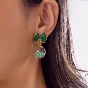 Close-up detail of green glitter bow earrings with a crystal ball on model's ear
