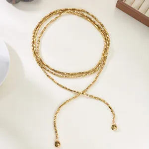 Detail view of golden cube bead wrap necklace with Y-shape tassel and drop pendants.
