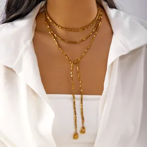 Close-up of a multi-layer gold cube bead Y-necklace with tassel pendants on a model.