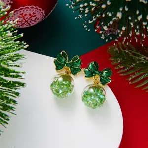 Detailed close-up of green bow earrings with sparkling glitter snow globe charms