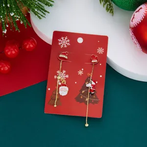 Detailansicht asymmetrischer Weihnachtsmann- und Tannenbaum-Ohrringe auf roter Karte.