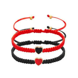 Close-up van drie handgeweven armbanden met hartvormige bedeltjes in rood en zwart.